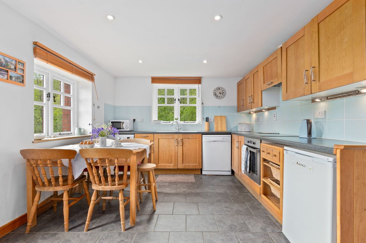 Kitchen with wooden units, slate floor and dining table