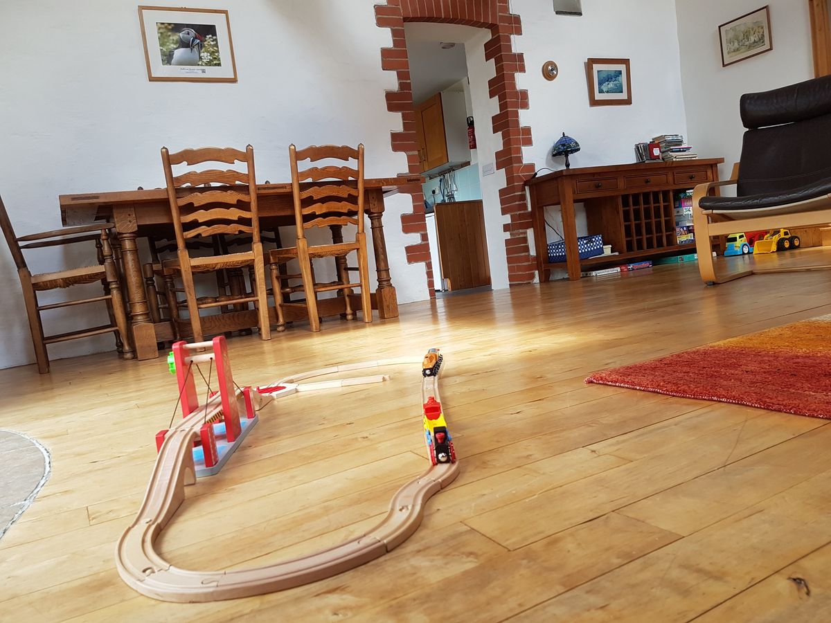 A wooden toy train set laid out on the living room floor